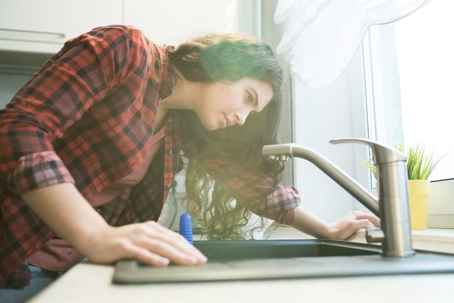 woman looking at dripping faucet